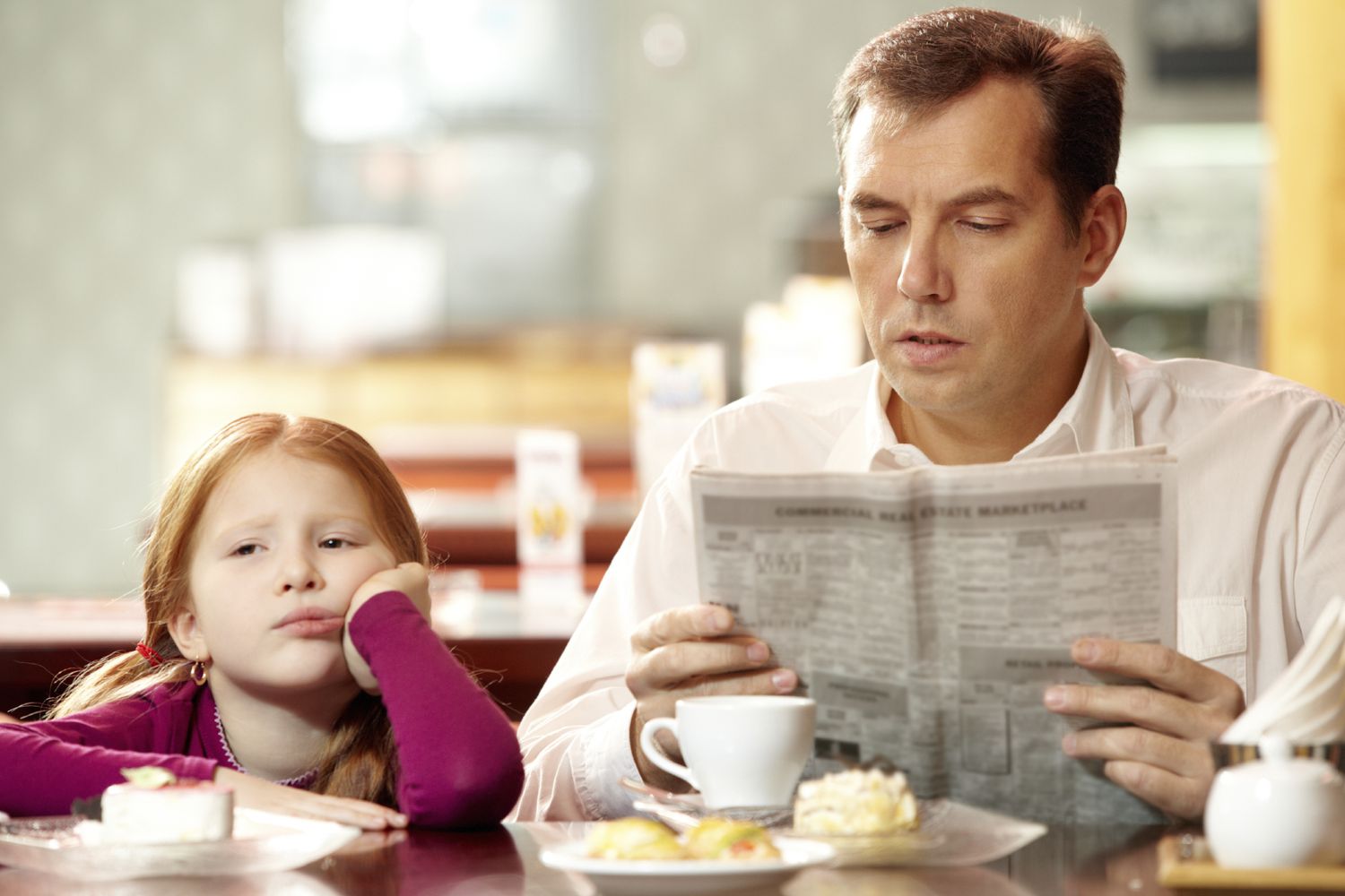 A parent and child at the breakfast table not talking to each other