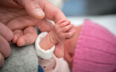成人握着新生婴儿的手