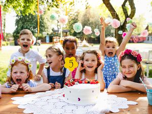 夏天的花园里，孩子们拿着蛋糕围在桌子旁参加生日聚会