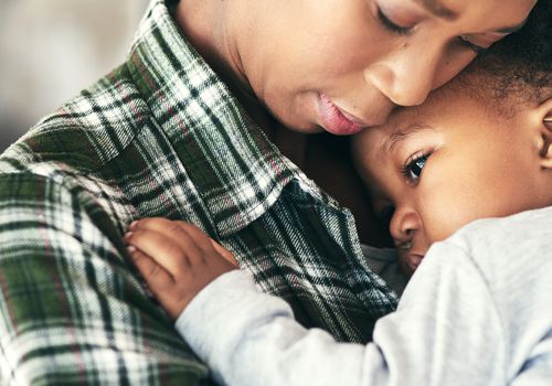 Parent cuddling sick toddler