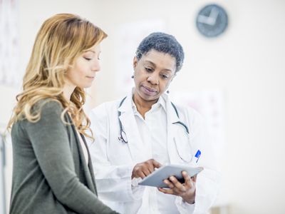woman and female doctor looking at tablet in office