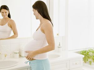 孕妇把手放在肚子上照镜子。