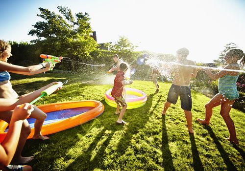 Kids having fun with squirt guns in a backyard
