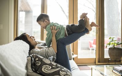 妈妈坐在沙发上，蹒跚学步的孩子坐在她腿上