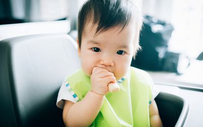 可爱的婴儿吃婴儿手指饼干在高椅子-股票照片