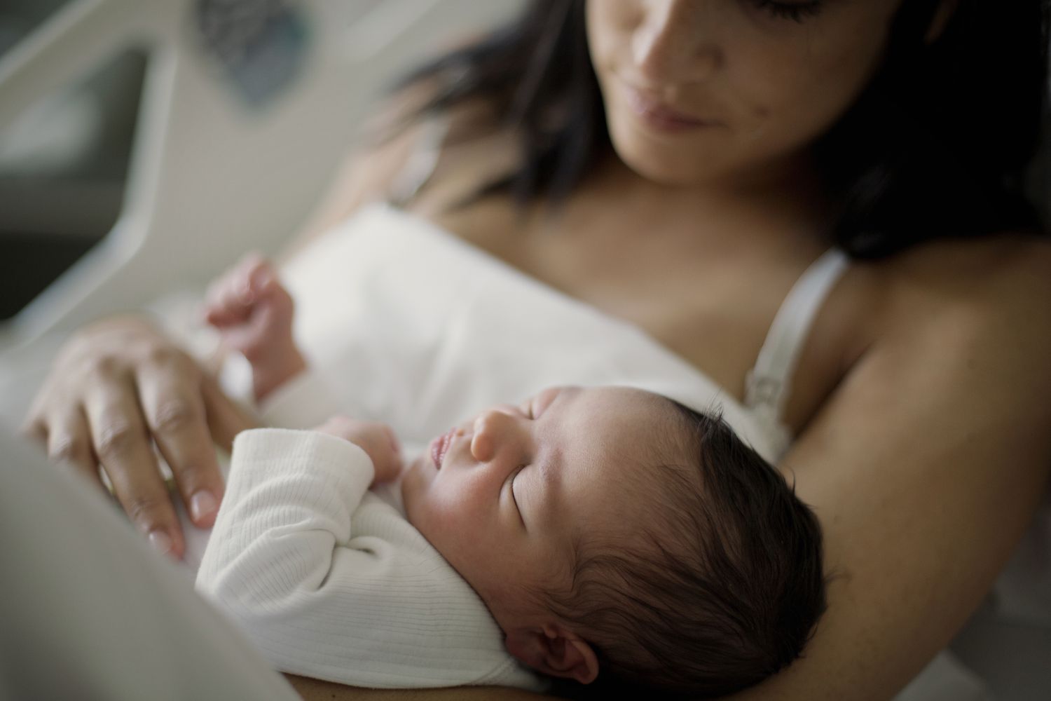 Close up of newborn girl with mom at bed in hospital