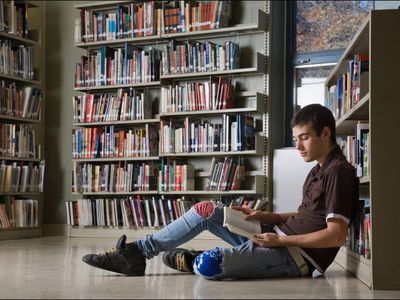Photo of Teen Boy Reading in Library