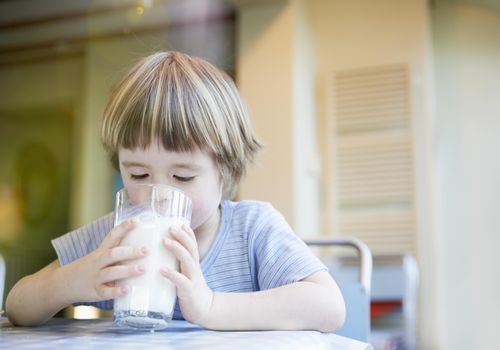 Young child drinking large glass of milk
