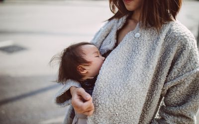 母亲用婴儿背带抱着正在哺乳的婴儿
