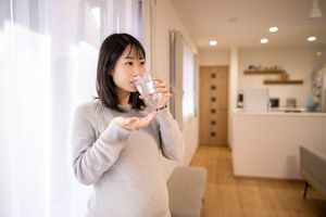Pregnant woman taking medicine in living room