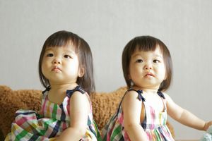 双胞胎女孩穿着一模一样的衣服坐在一起咳嗽