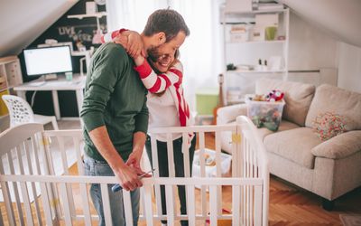 expecting father helping wife build crib for baby