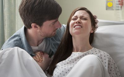 一名男子牵着一名妇女在医院分娩
