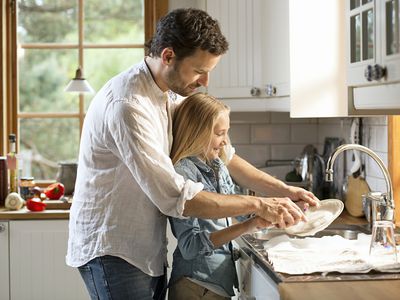 Father washing dishes with his daughter