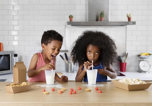 Brother and sister drinking milk in the kitchen