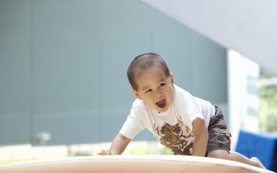 蹒跚学步的孩子在体育馆的垫子上爬