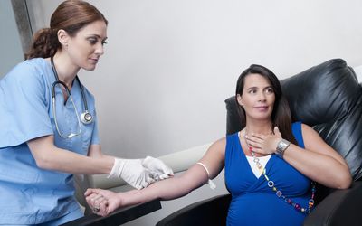 Female doctor taking blood sample of a pregnant woman