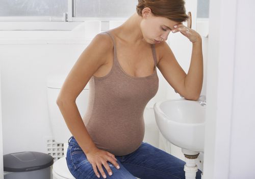 Pregnant woman in bathroom leaning over sink