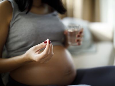 Pregnant woman holding a pill and a glass of water