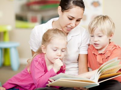 A nanny reading to two children