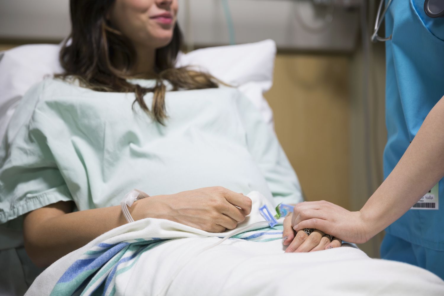 Nurse holding hands with pregnant woman in hospital