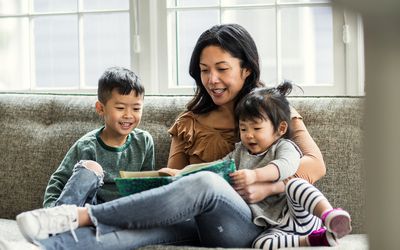 一位母亲坐在沙发上给孩子们读书