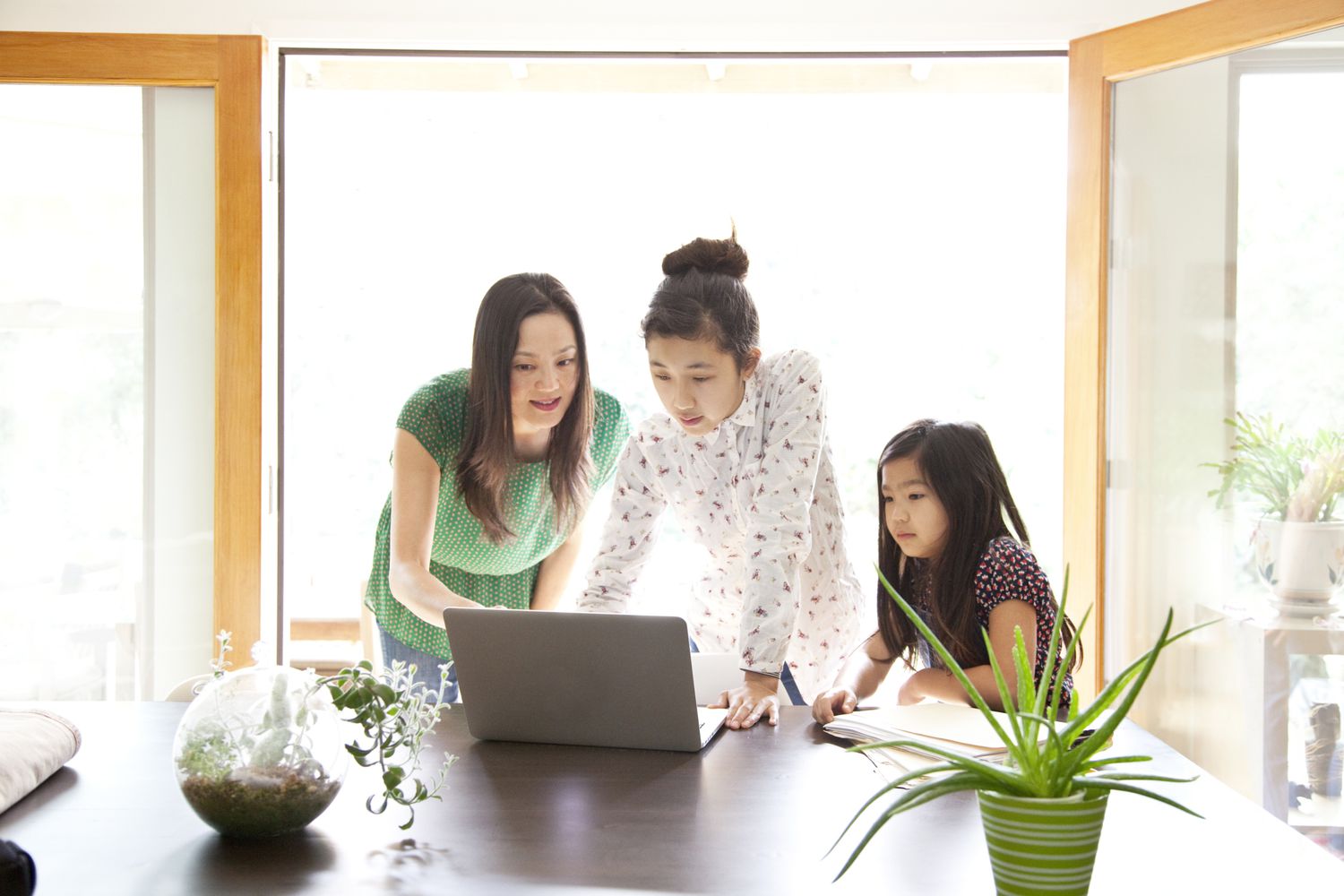 Mother looking over daughter's shoulder at laptop