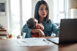 妈妈抱着孩子在电脑前工作