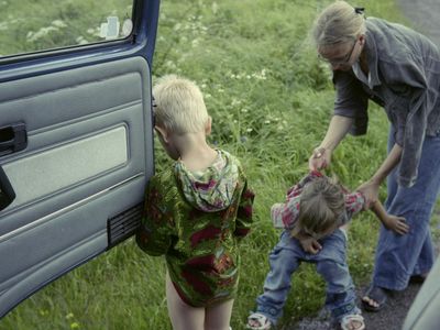 A mother helping her children to pee on a roadside, Sweden
