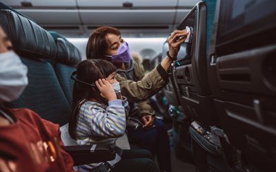 mom disinfecting tv screen for child on an airplane