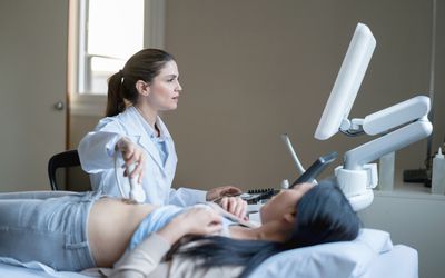 Female doctor doing an ultrasound scan looking very focused to a patient
