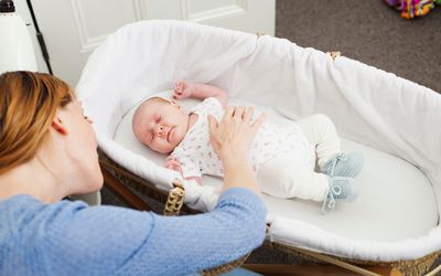 Mother comforting newborn daughter in bassinet