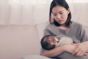 女人严肃地坐在那里，怀里抱着孩子