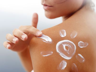 tanned body of young woman in summer with sunscreen lotion in shape of sun