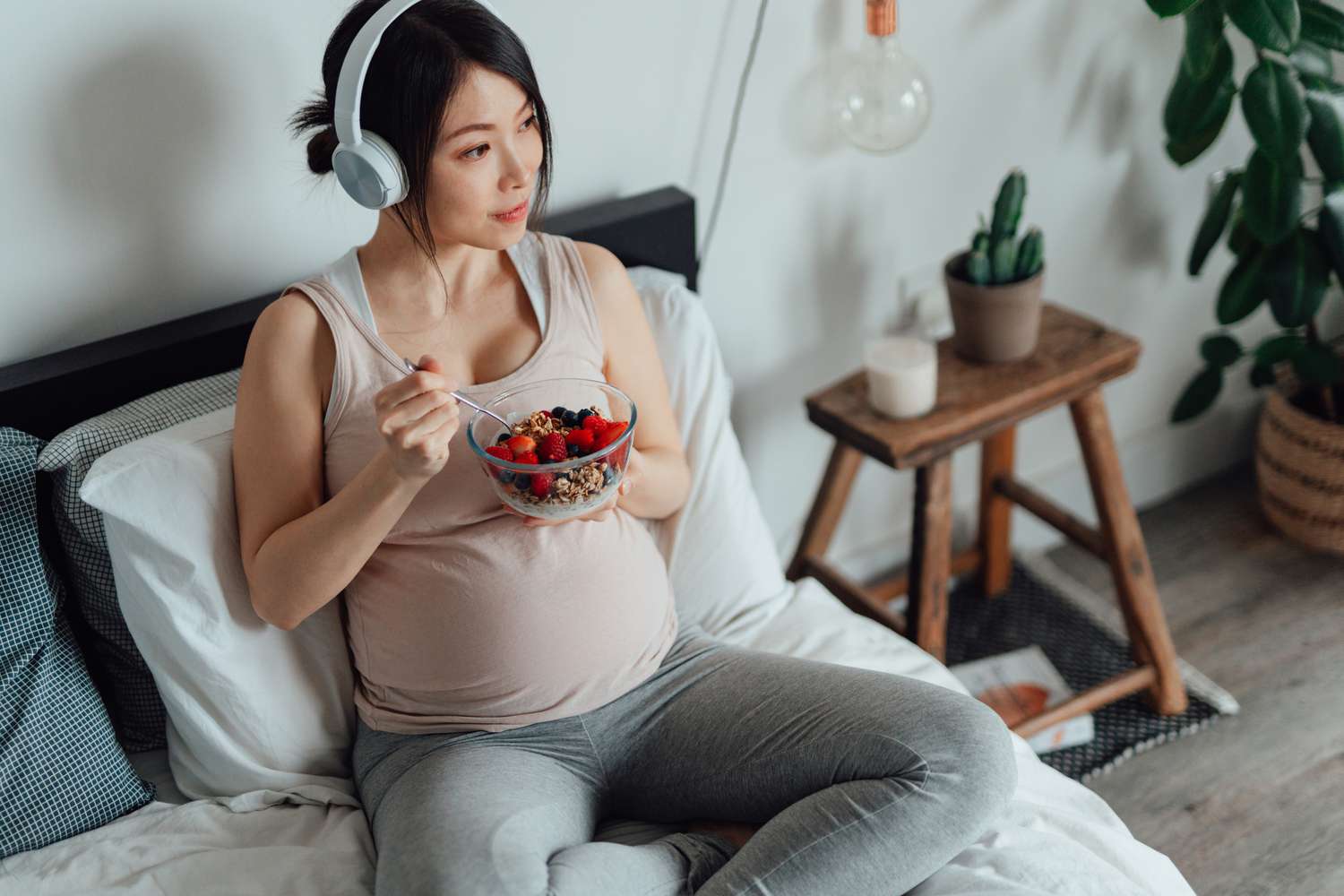 孕妇坐在床上吃浆果，听音乐