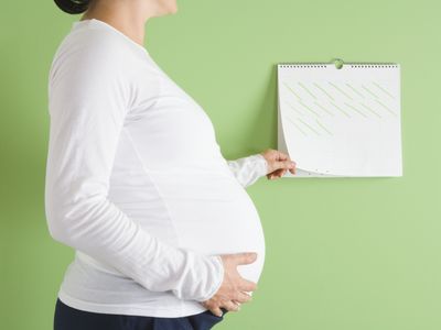 Pregnant woman standing in front of calendar