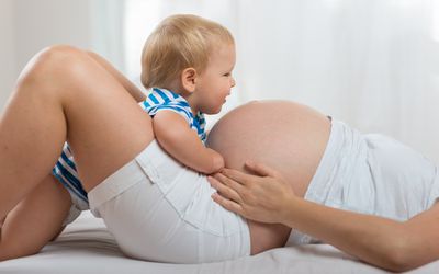 幸福的家庭。孩子男孩看着怀孕母亲的肚子