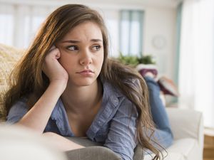 一个十几岁的女孩独自坐在沙发上。