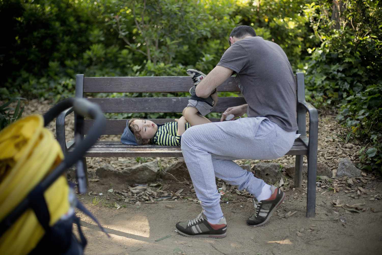 Dad changing his child's diaper on a park bench