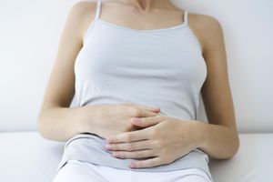 Woman holding stomach, cropped view