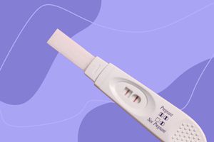 Stick pregnancy test displayed against a purple patterned background