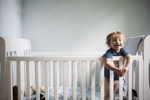 toddler standing and smiling in crib