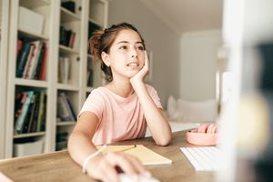 Teenage girl in a pink shirt sitting at a computer