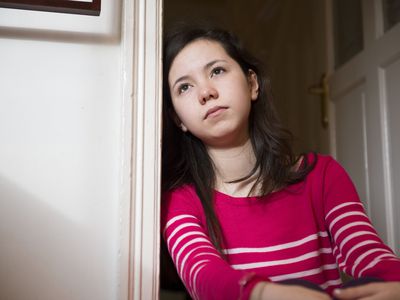 Moody girl leaning against doorway