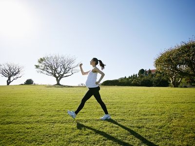 A pregnant person walks across a grassy field