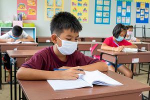 child wearing a face mask at a school desk