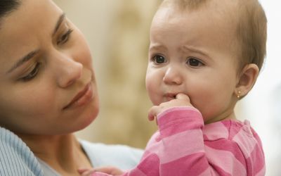 Hispanic mother holding unhappy baby girl