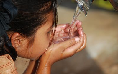 Girl drinking water being poured into her hands