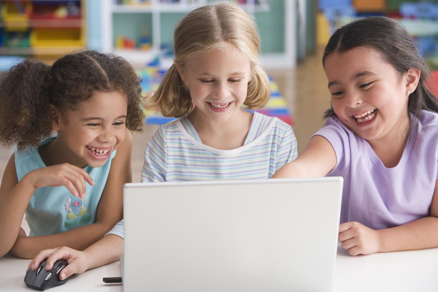 Schoolgirls (4-7) using laptop, smiling
