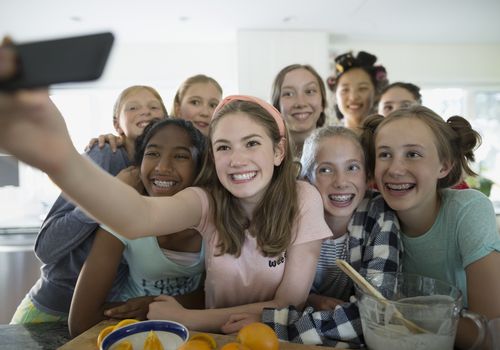 Girls taking a selfie while making breakfast after a slumber party